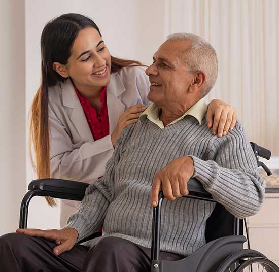 Elderly Indian man in wheelchaire being cared for by a female nurse